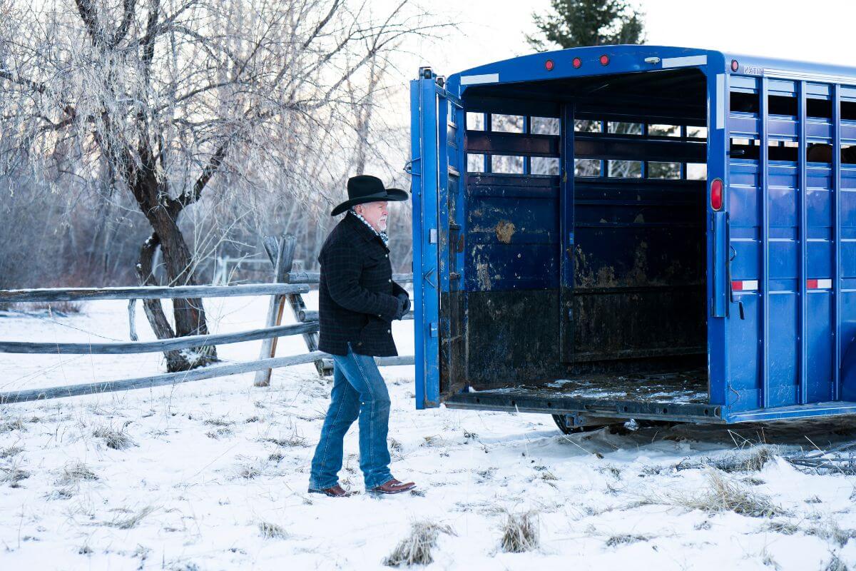 A man standing next to a blue horse trailer in Montana.