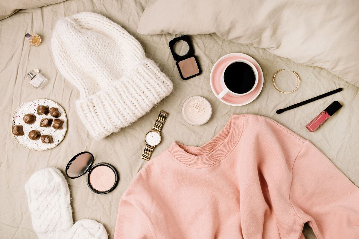 A pink sweater and other items are laid out on a bed as part of a Montana trip for spring.