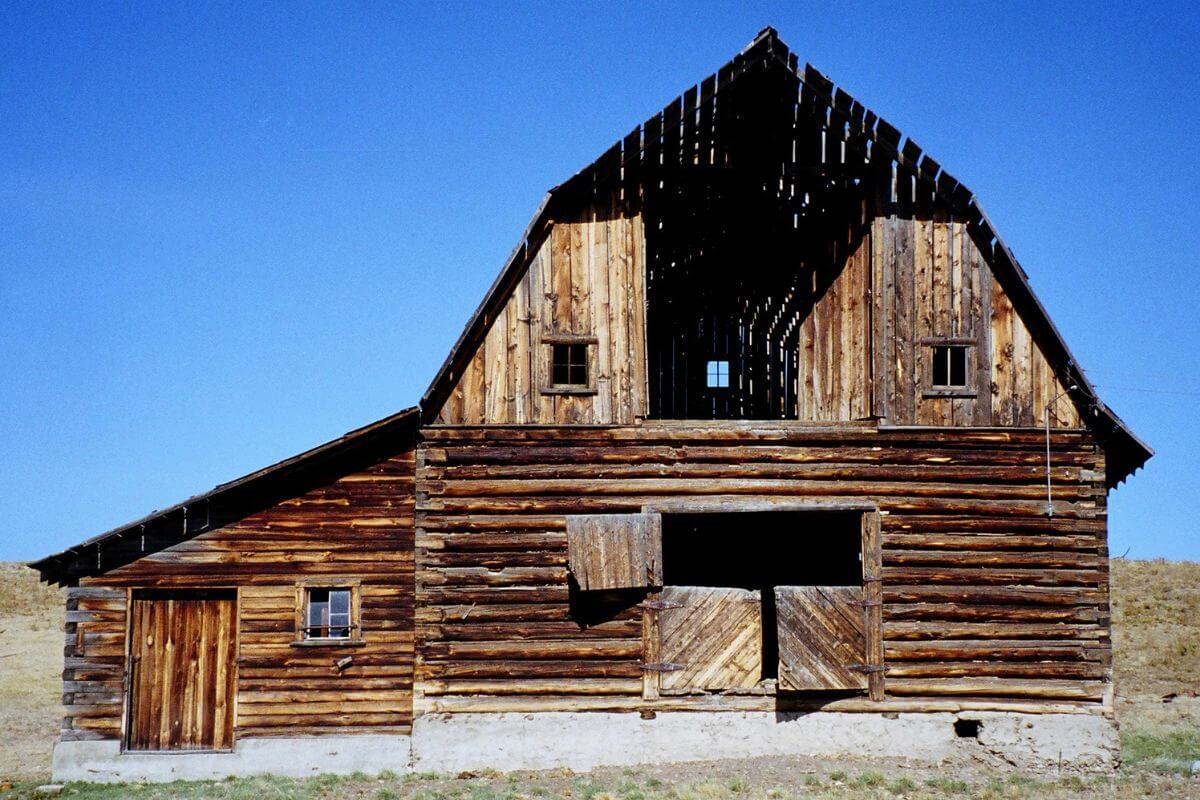 An old wooden barn sitting in the middle of a field in Montana.