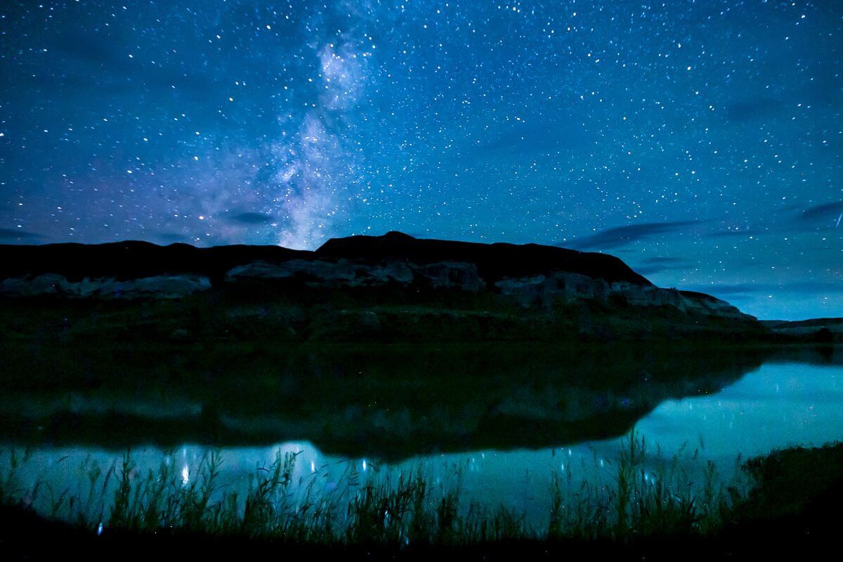 A Starry Sky Over a Lake Set Against a Backdrop of Mountains in Montana