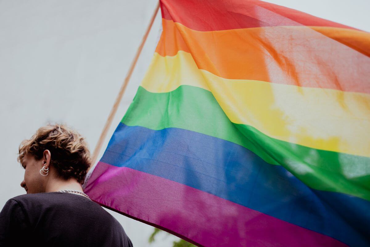 A gay man proudly holds a rainbow flag during a gay and lesbian travel Montana.