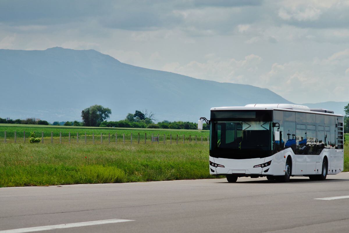 A modern white bus from Big Sky Bus Tours travels along a road during one of their Montana bus tours.