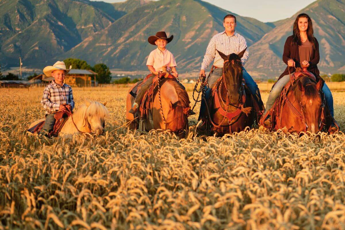 A family on horseback enjoying a scenic field during the golden hour while on their Montana vacation.