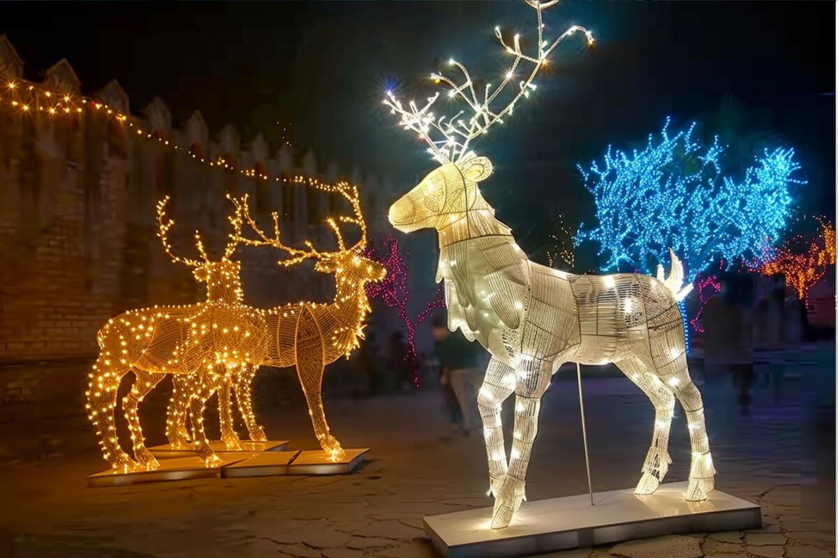 A group of illuminated reindeer statues in a courtyard in ZooMontana during the Holiday Nights event.