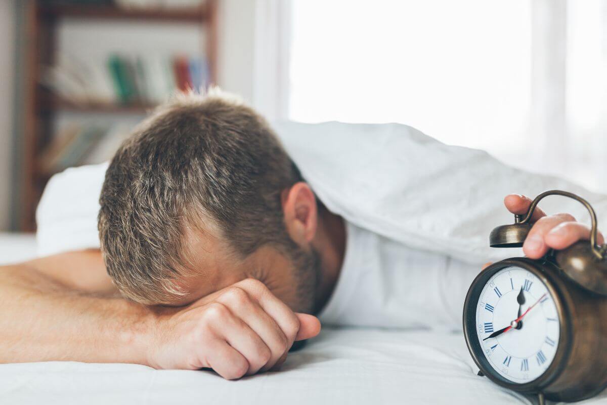 A man laying with an alarm clock 