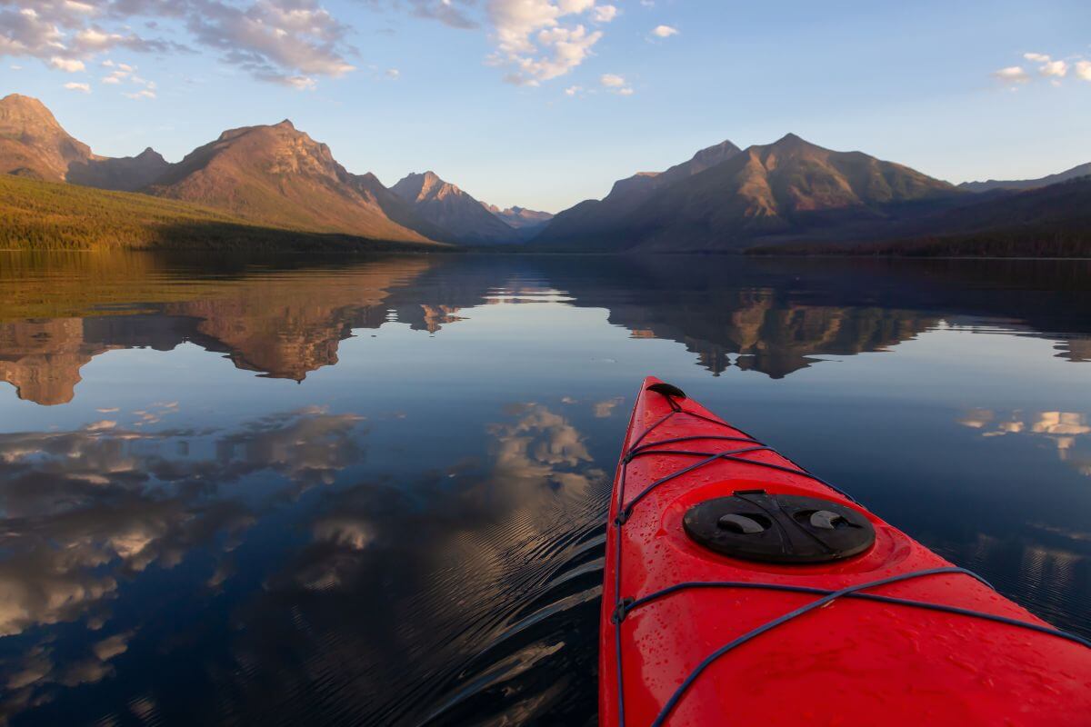 A red kayak gliding on Lake McDonald in Montana with mountains in the background.