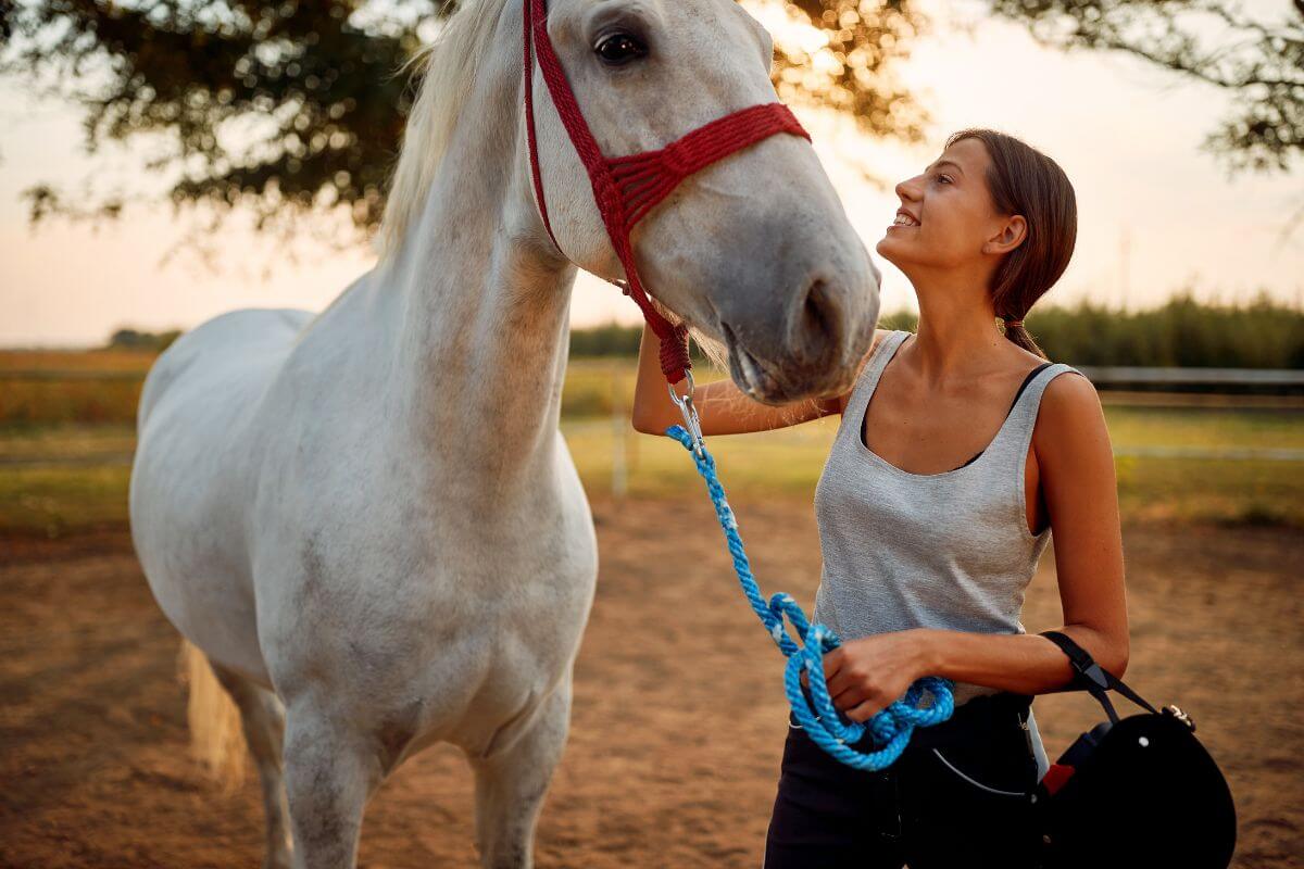 A woman is petting a white horse at a ranch in Montana.