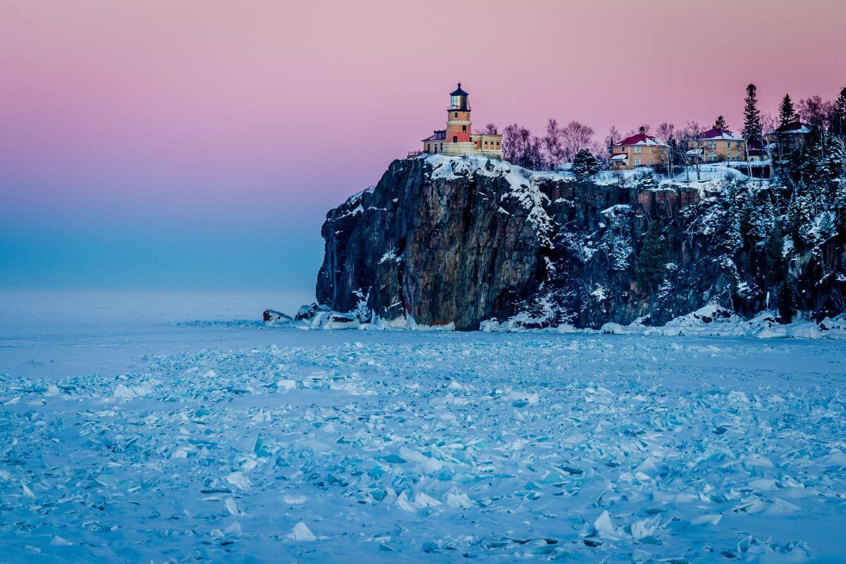 A lighthouse sits on top of a snowy rocky cliff in Minnesota, one of the coldest states in the U.S.
