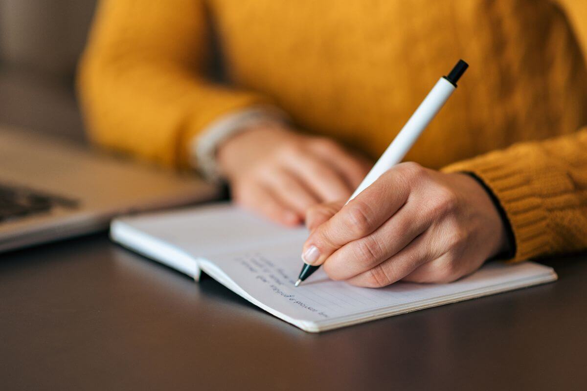 A woman in Montana jotting notes in a notebook using a pen.