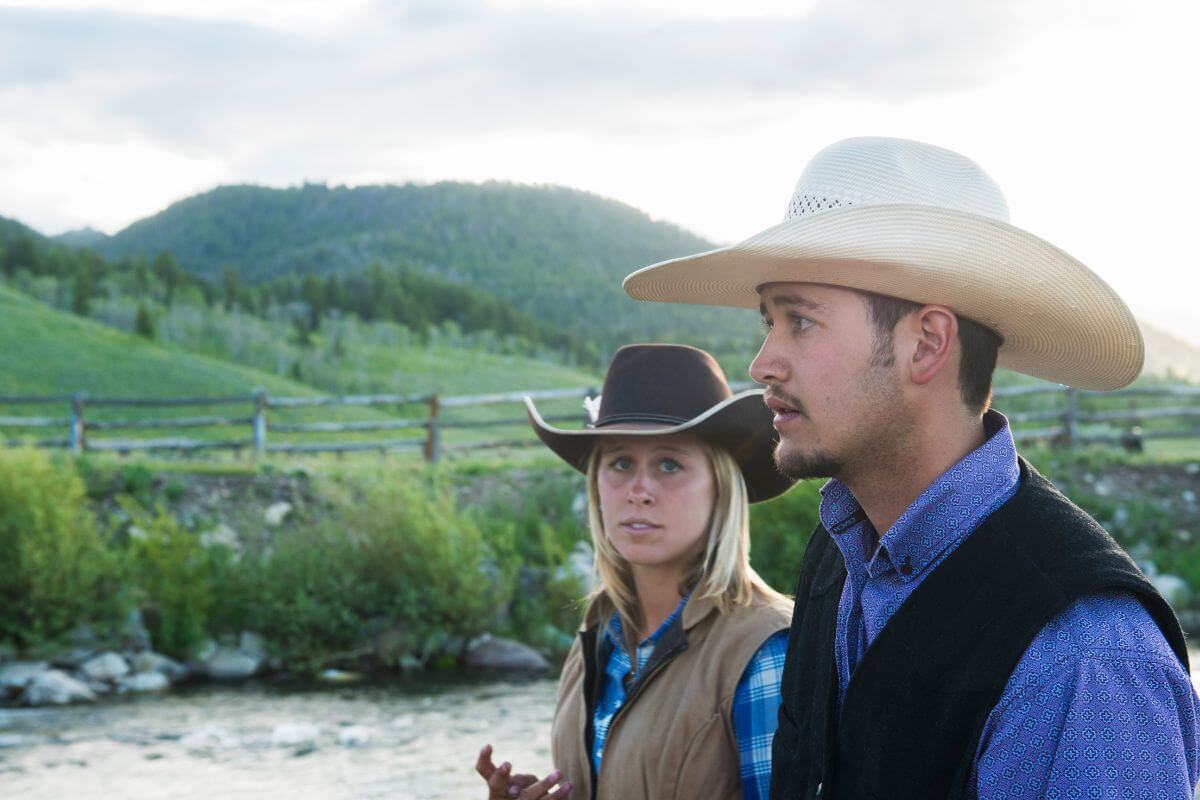 A man and woman in cowboy hats standing next to a river in Montana.