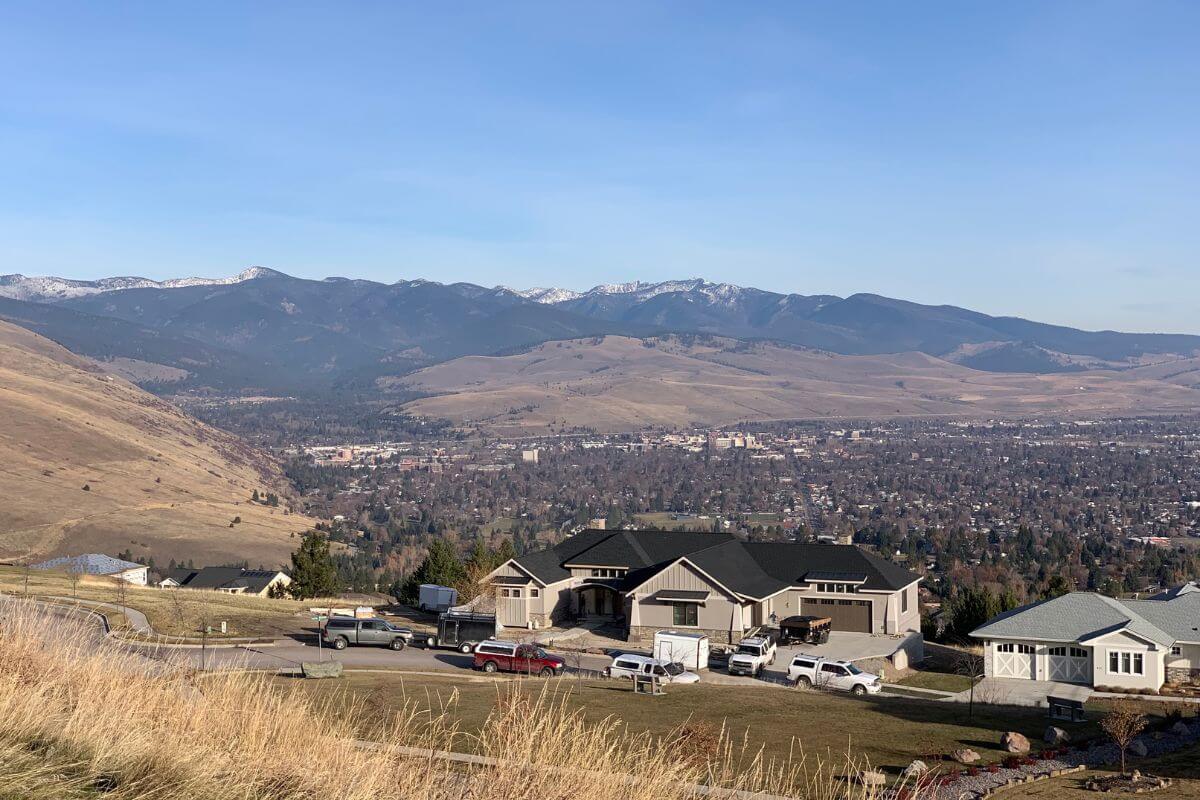 The view from the top of a hill overlooks a city and mountains in Montana.