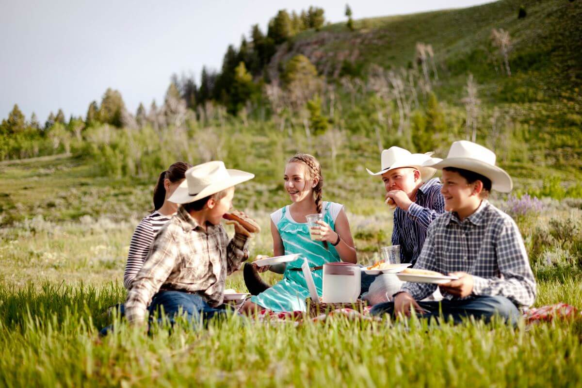 A group of people in cowboy hats enjoying a picnic in Montana.
