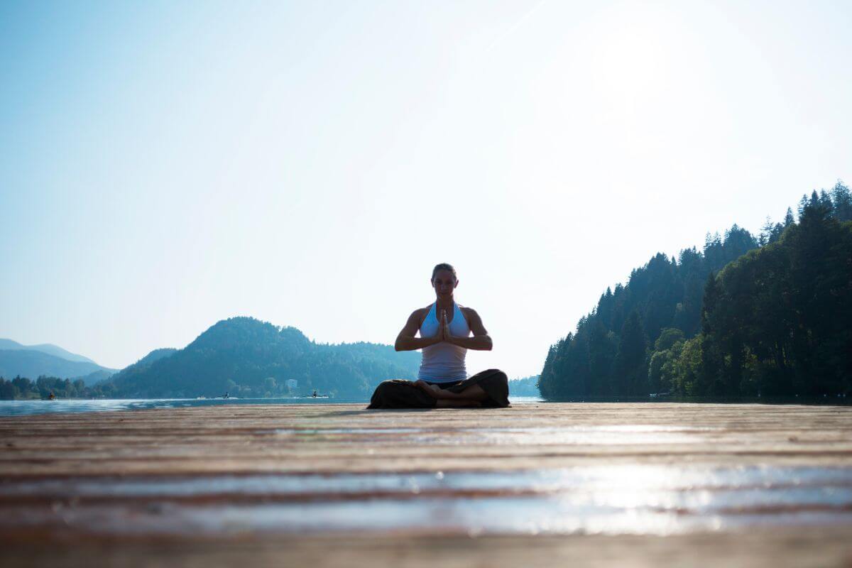 A woman is meditating on a dock near a lake in Montana.