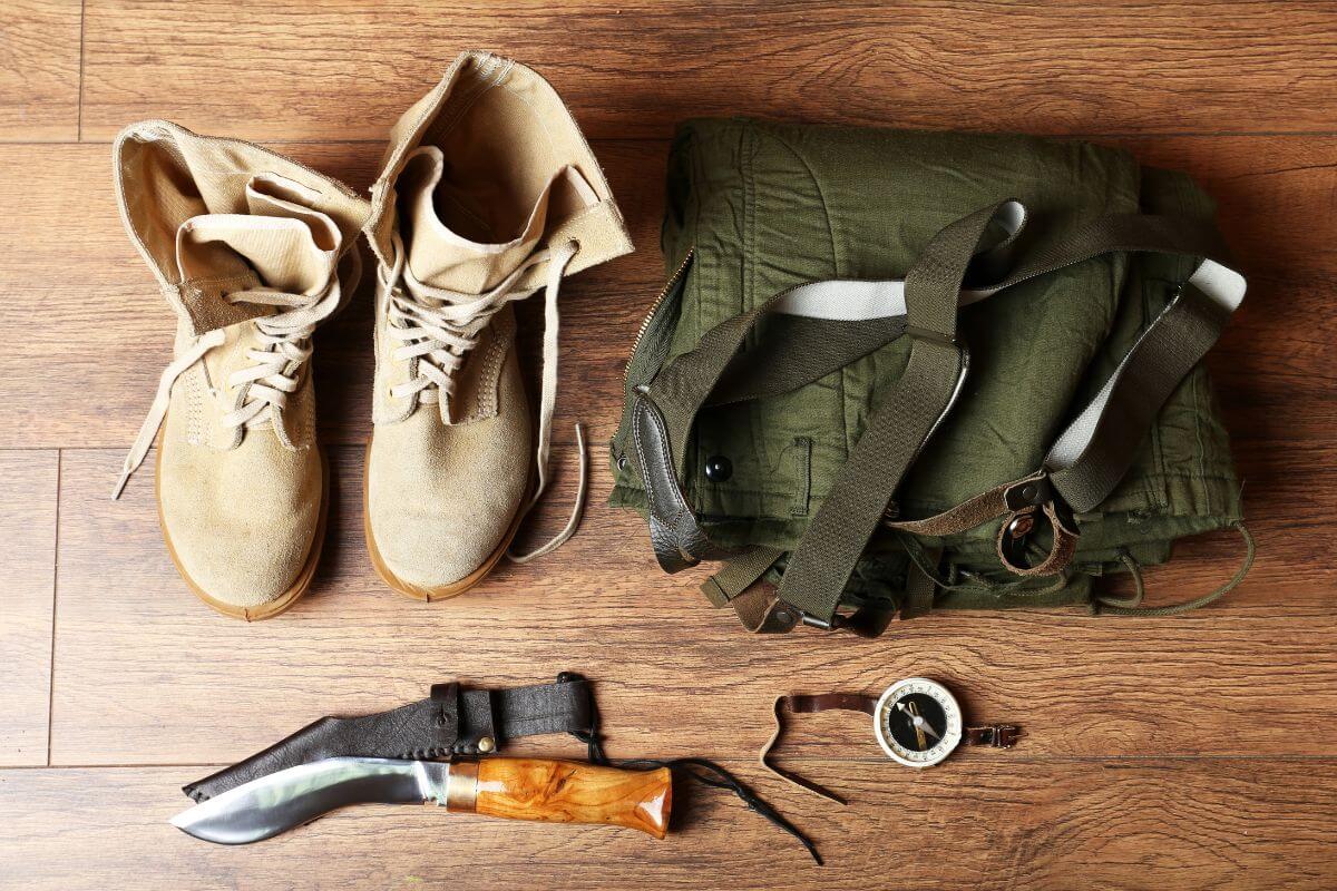 Squirrel hunting gear, featuring a pair of boots, a knife, and a backpack, on a wooden floor