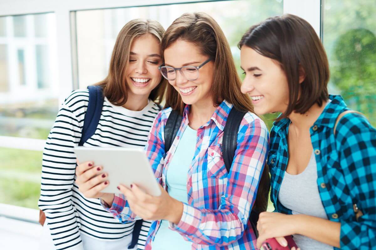 Three young women are looking at a tablet computer in Montana.
