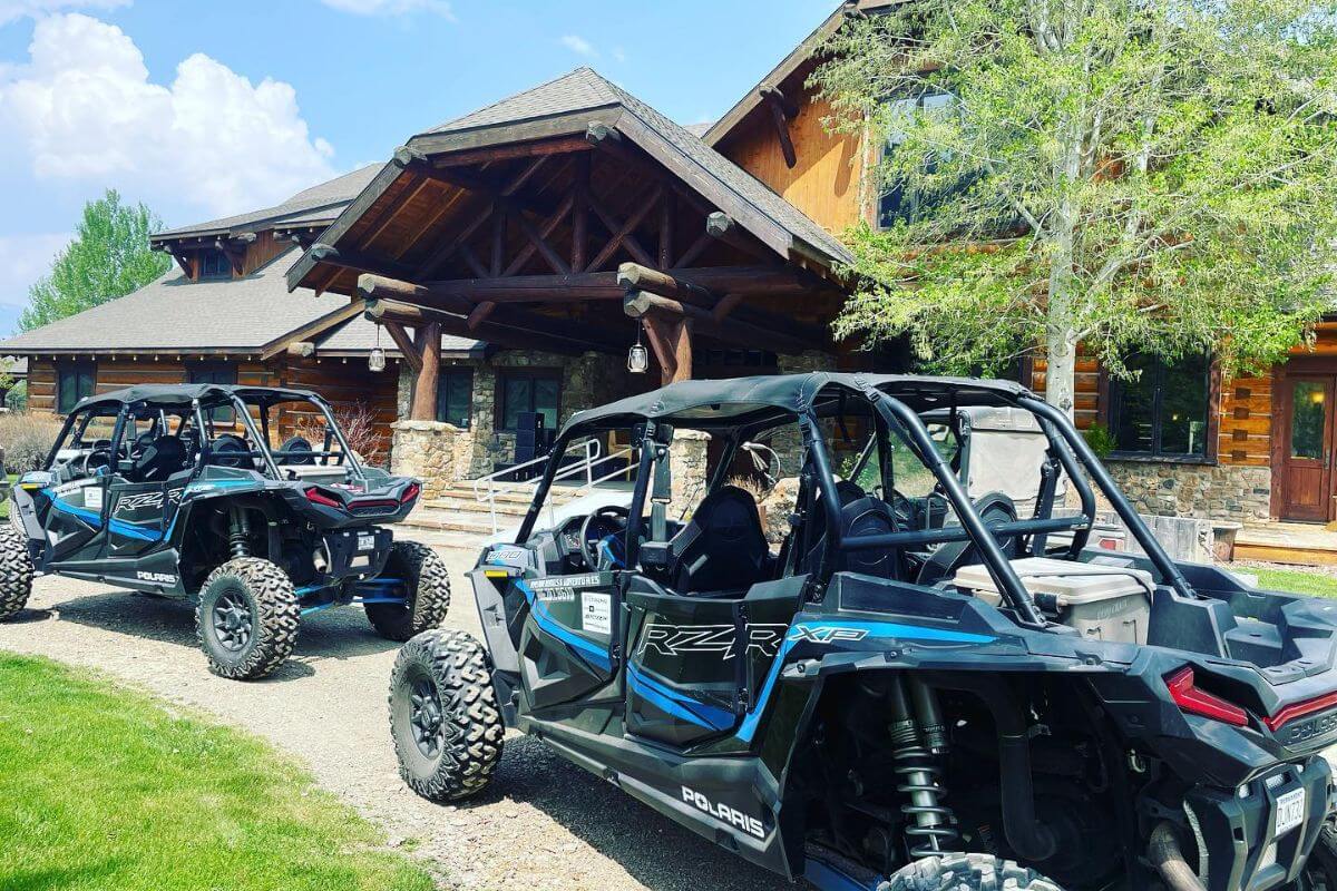 Off-road UTVs parked in front of a rustic, luxury mountain home at Silver Bow Club