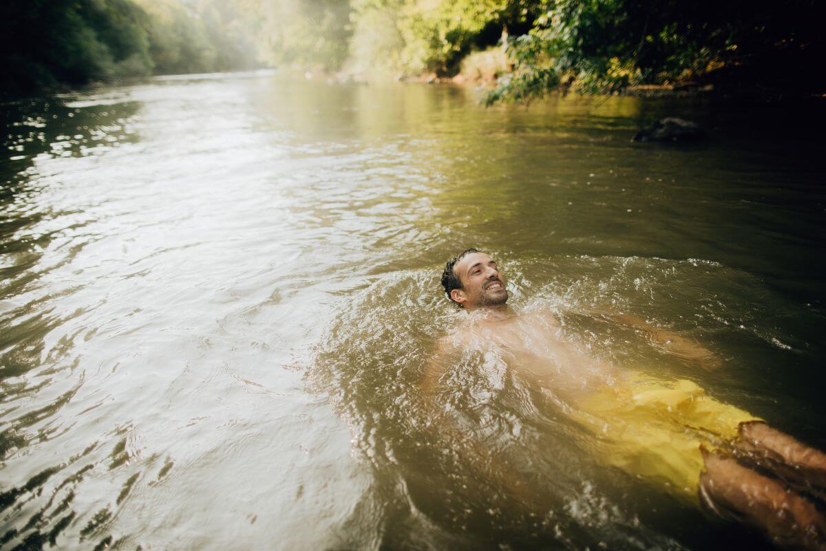 A man enjoys a relaxing float in a gently flowing river, surrounded by the lush nature of Ipasha Falls, Montana.