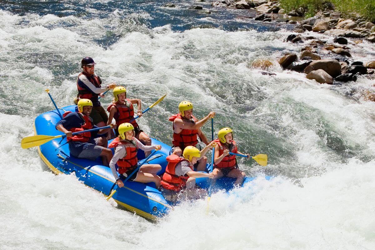 A group of people in helmets and life vests navigate the rough river rapids near Piegan Waterfall in Montana in an inflatable raft