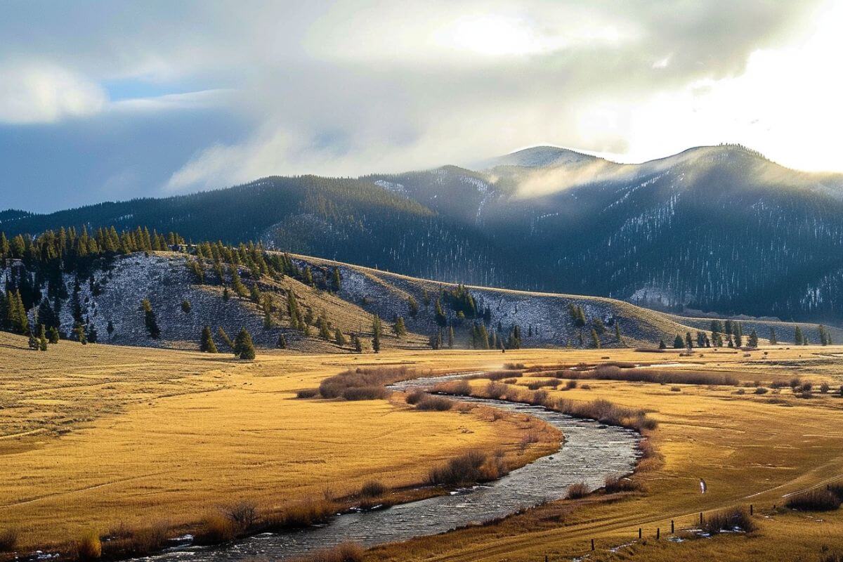 A river runs through a grassy field with mountains in the background in Montana afternoon.