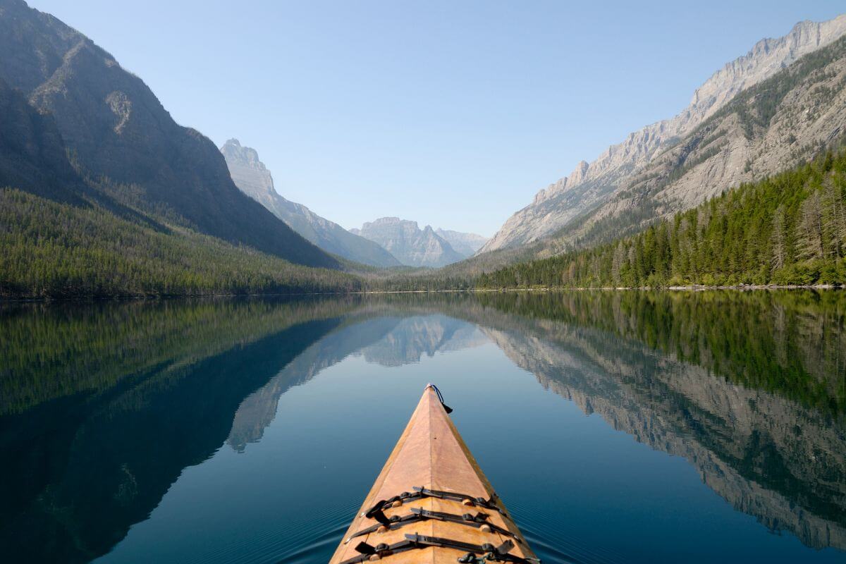 A tranquil canoe journey through a serene mountain lake, with mirror-like reflections near Ipasha Falls in Montana.