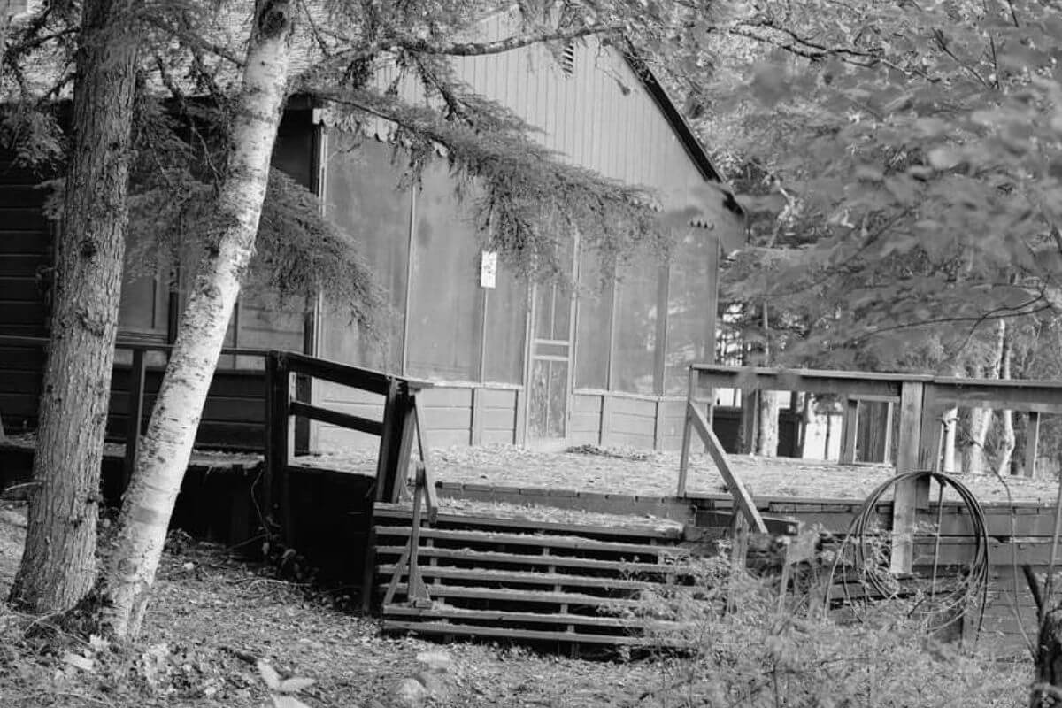 A black and white photo of a dilapidated cabin in the woods of Montana.