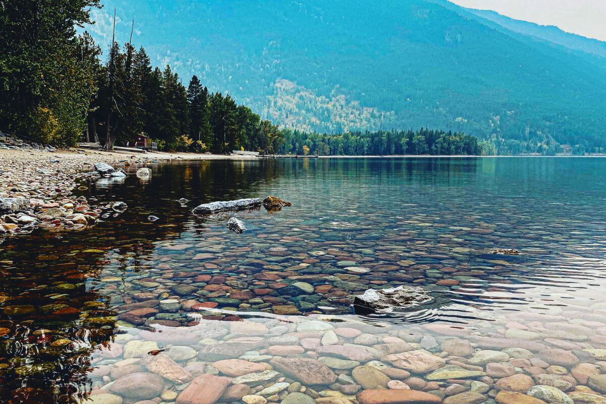 A serene lake nestled among trees and rugged rocks.