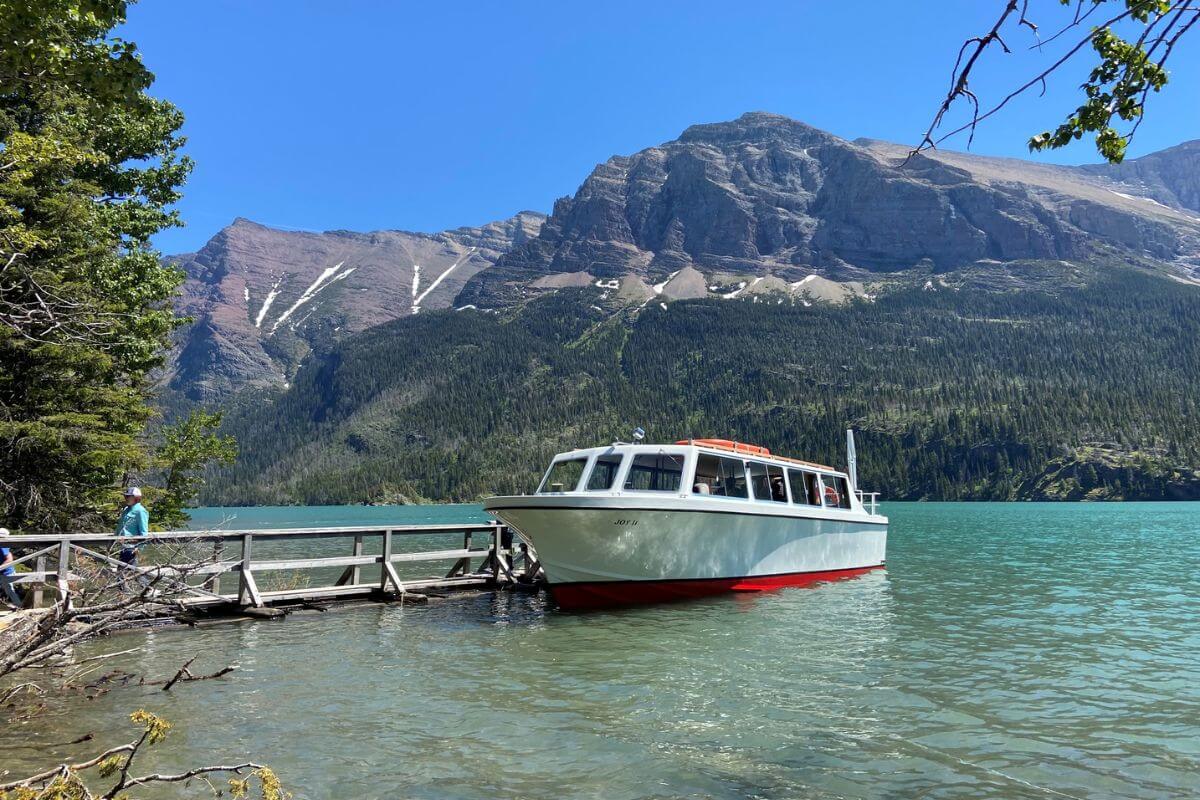 A boat docked at a wooden pier on a lake at Many Glacier, ready for a boat tour at Swiftcurrent Lake.