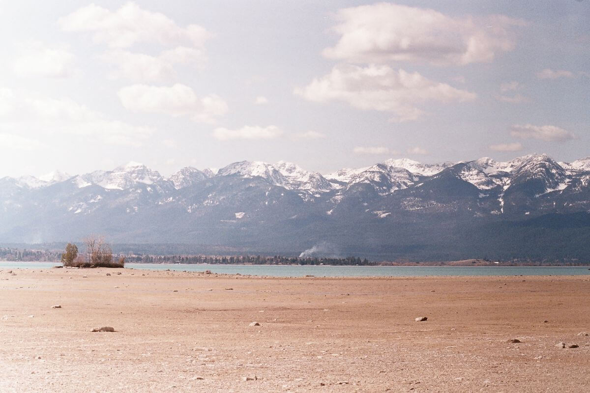A wide landscape featuring a dry, sandy area leading to a lake, one of the private lands for hunting in Montana.