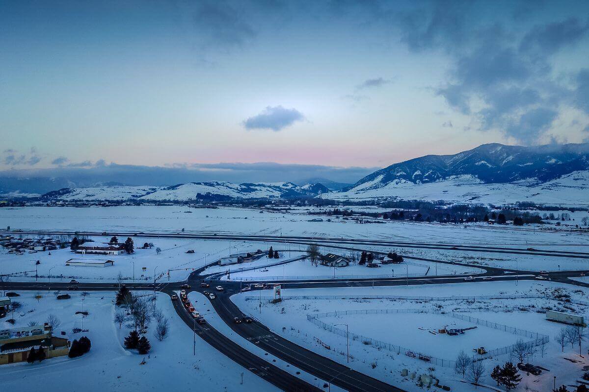 An aerial view of a snow-covered highway and mountains in Montana.