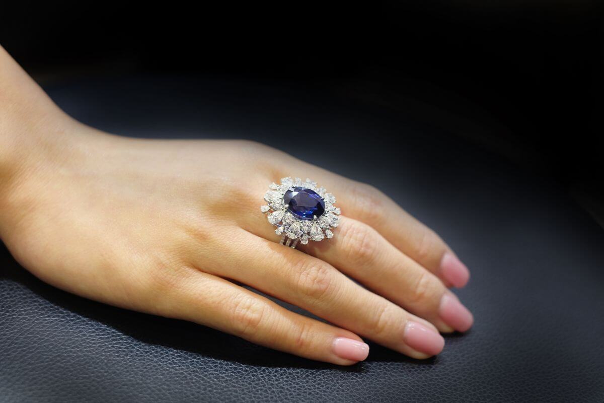 A woman's hand with a Montana Yogo Sapphire ring encrusted with diamonds.