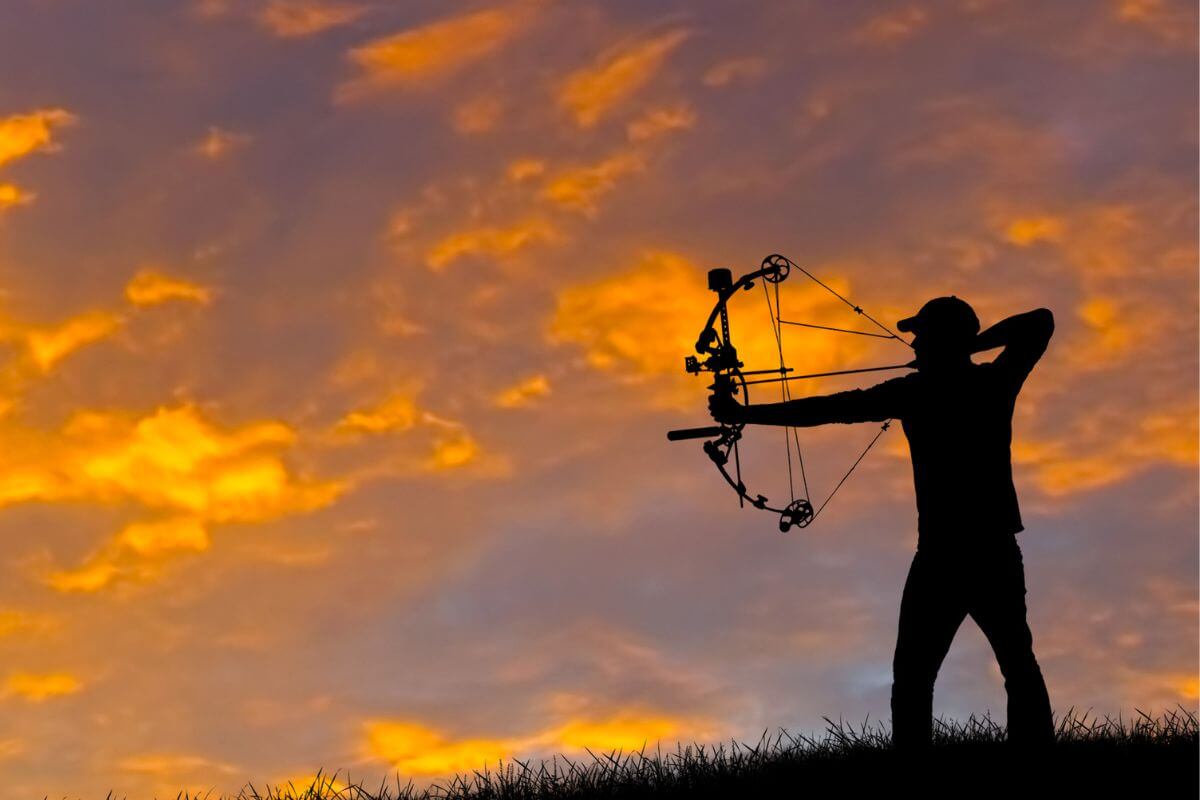 A man takes aim using his bow and arrow for hunting practice during the golden hour in Montana.
