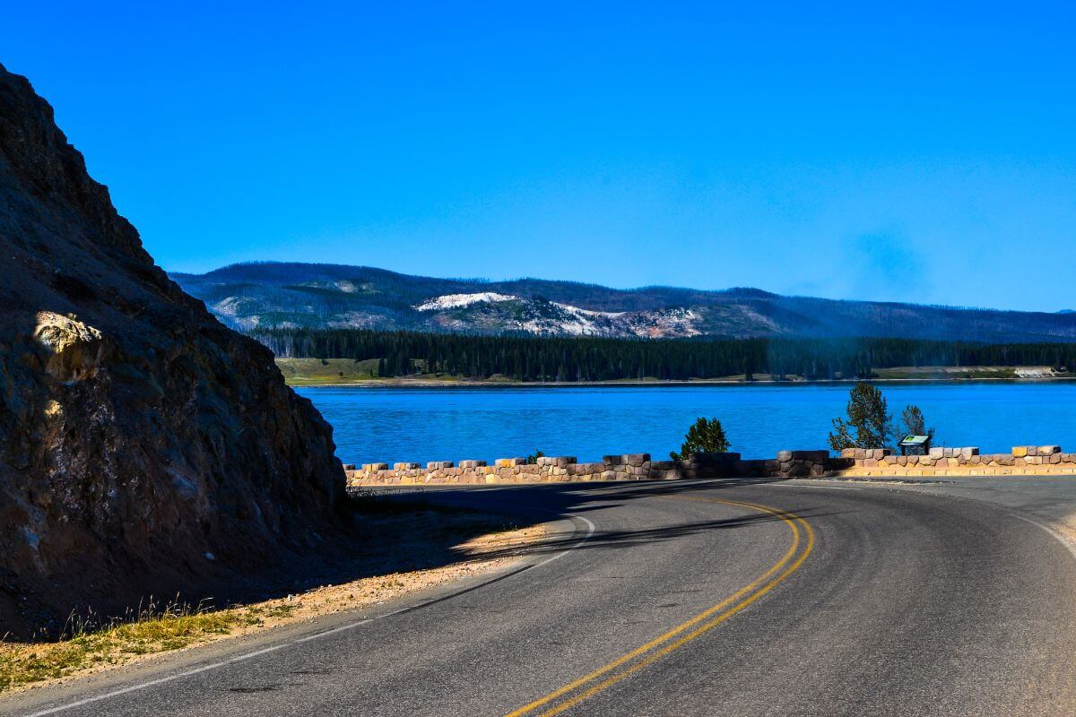 A scenic road in Montana leading to a serene lake overlooked by majestic mountains