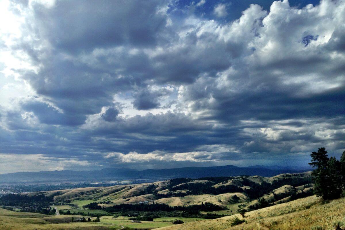 A cloudy sky over a grassy field and mountains in Montana.