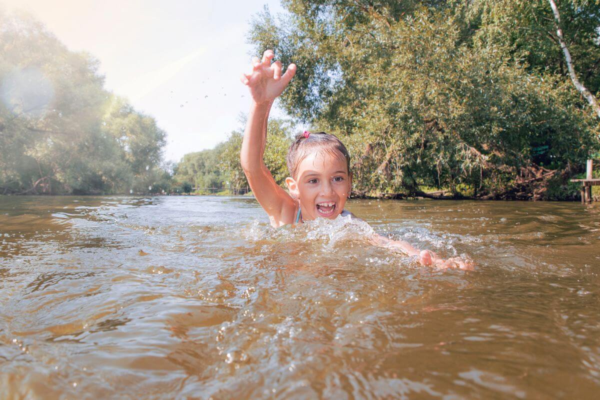 A little girl swims in a lake near Knowles Falls, which is generally a safer area for swimming.