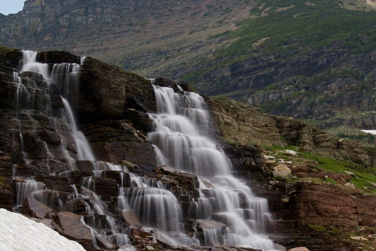 The picturesque Oberlin Waterfall as it tumbles over rugged, layered rocks amid a mountainous landscape