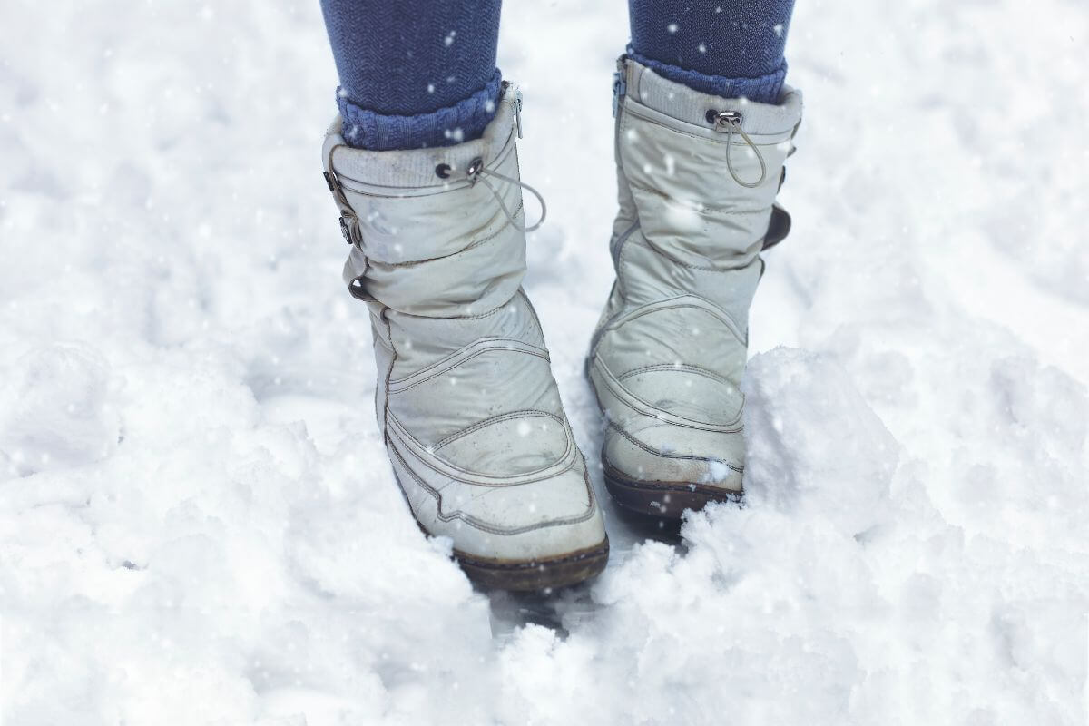 A woman wearing snow boots standing in the snow in Montana.