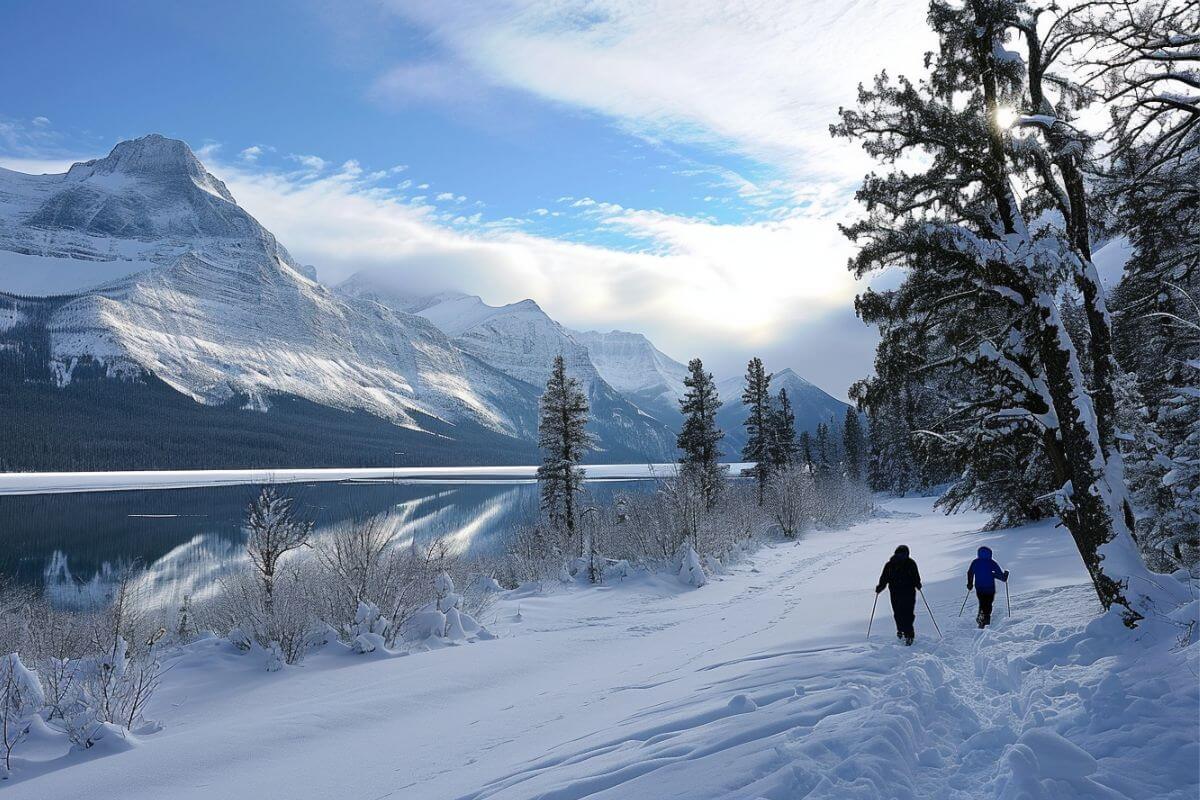 Two people skiing along a snow covered path near a lake in Montana during winter.