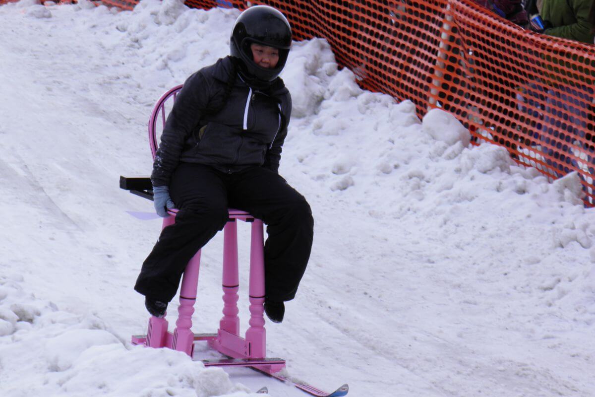 A person sitting on a barstool with ski attached in the snow in Montana.