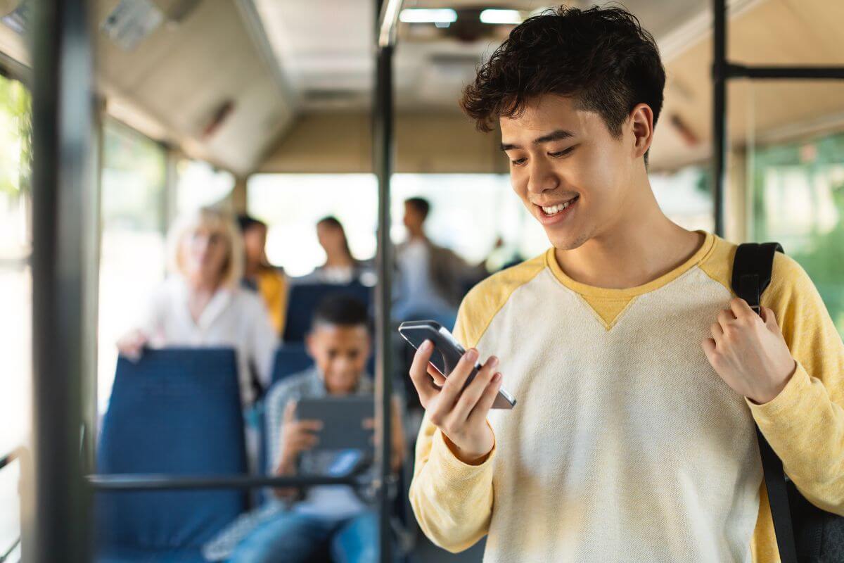 A young man on a bus in Montana looking at his phone.
