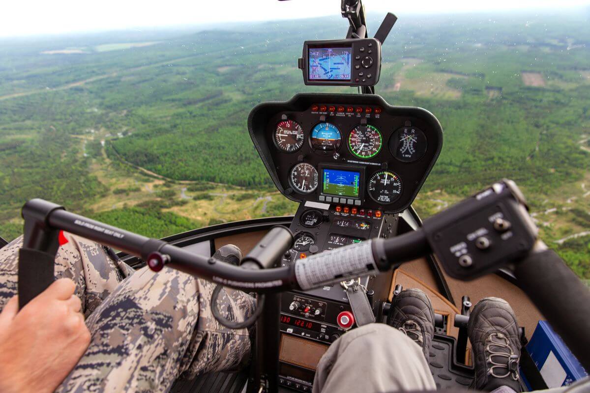 The pilot's view from the cockpit showcases a sprawling lush landscape below during one of Montana's premier helicopter tours.
