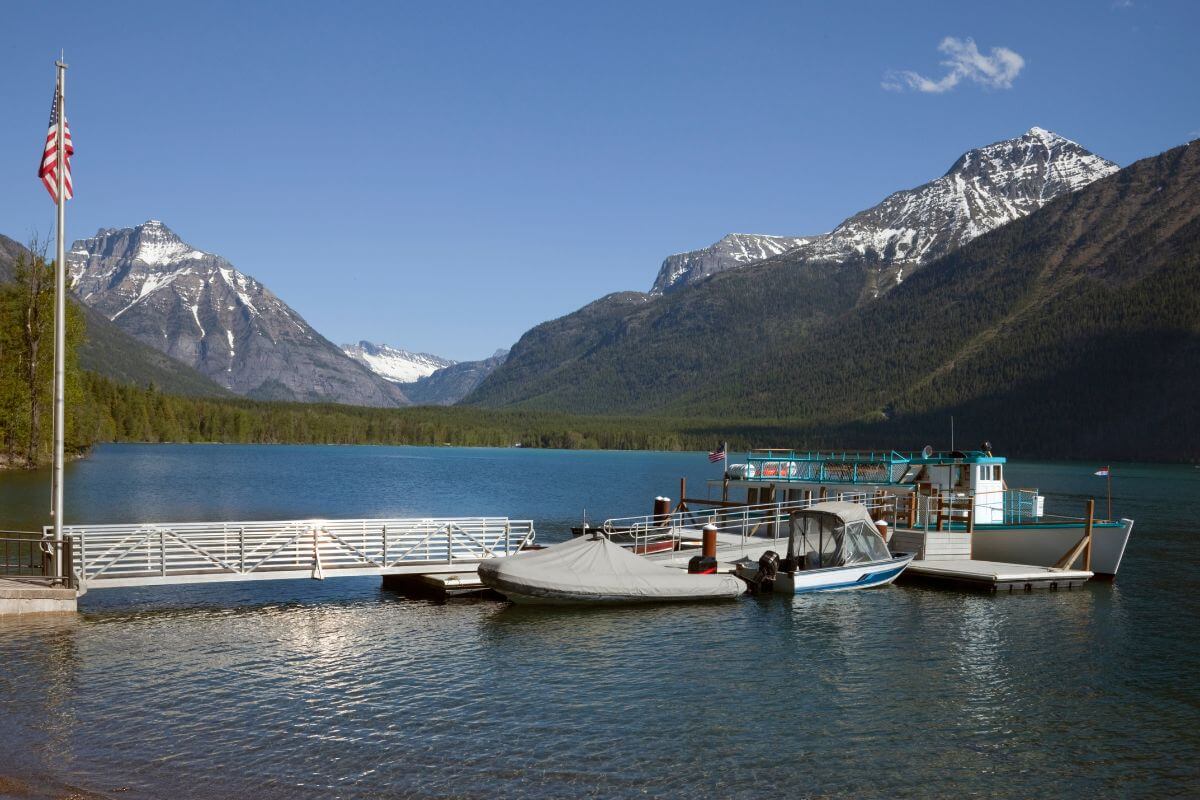 A boat docked in the lake Mcdonald with majestic mountains as the backdrop, offering a picturesque sight for fall activities in Montana.