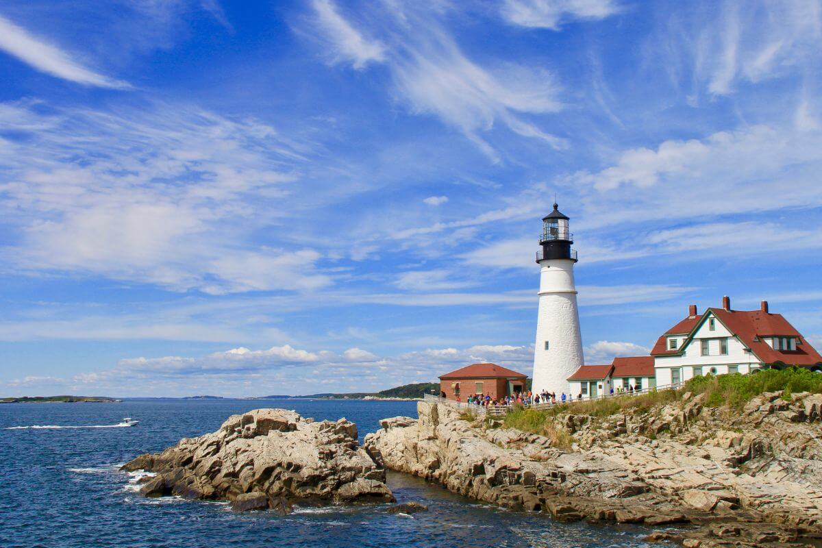 A lighthouse sits on top of a rocky cliff in Maine.