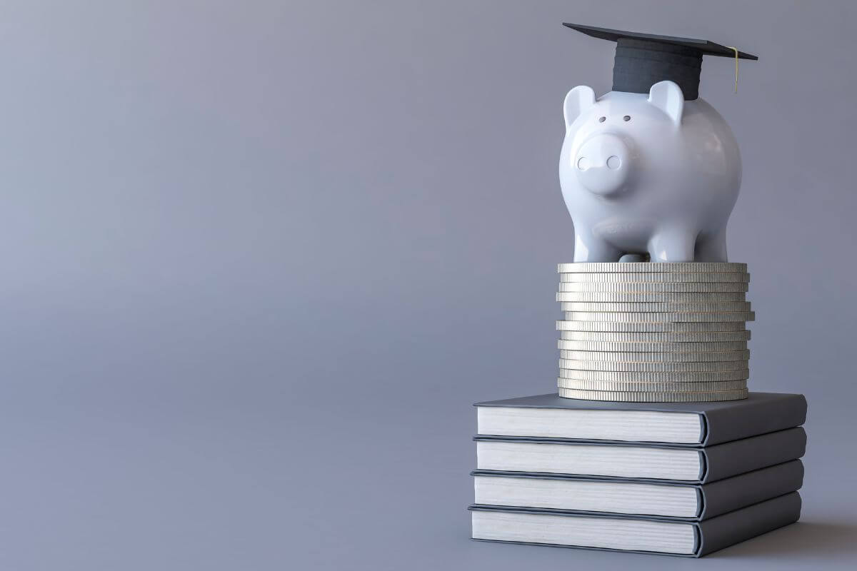 A piggy bank sits on a stack of coins and books