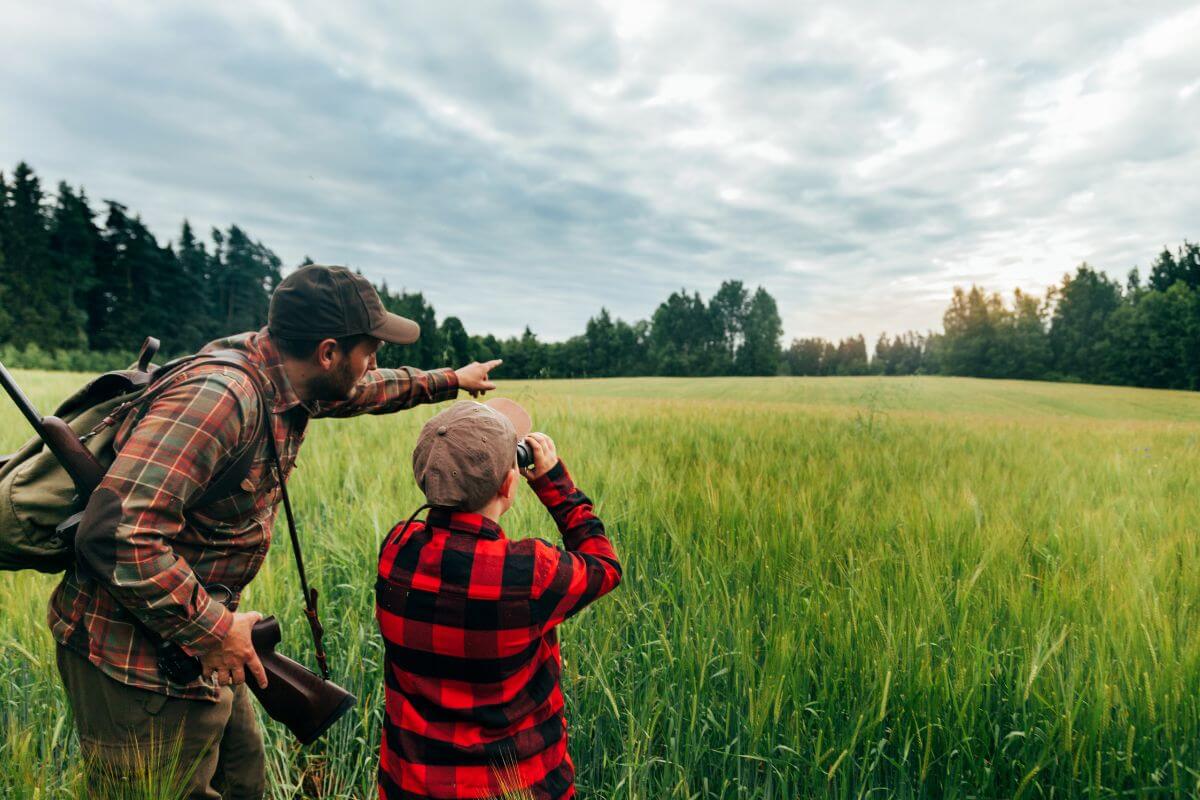 A young man is being taught by his father to scout the surroundings for game during a Montana hunting trip.