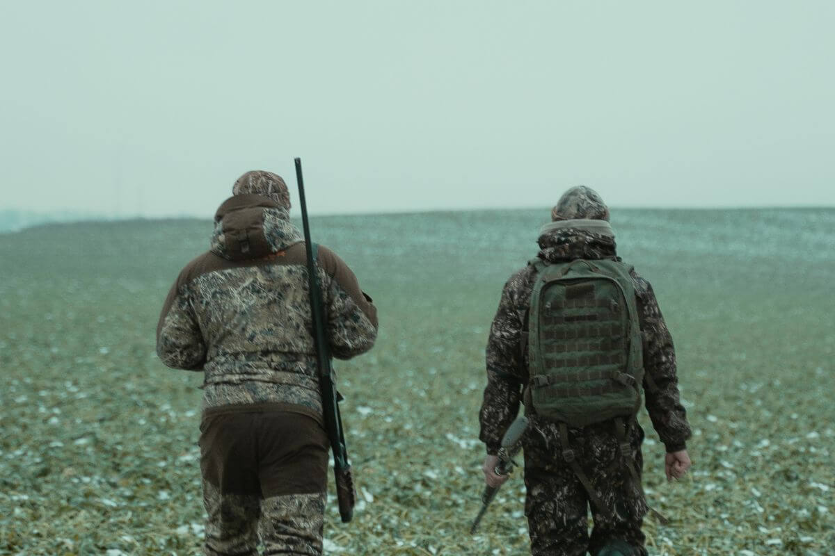 Two hunters in camouflage trekking through a field in Montana in search of prey.