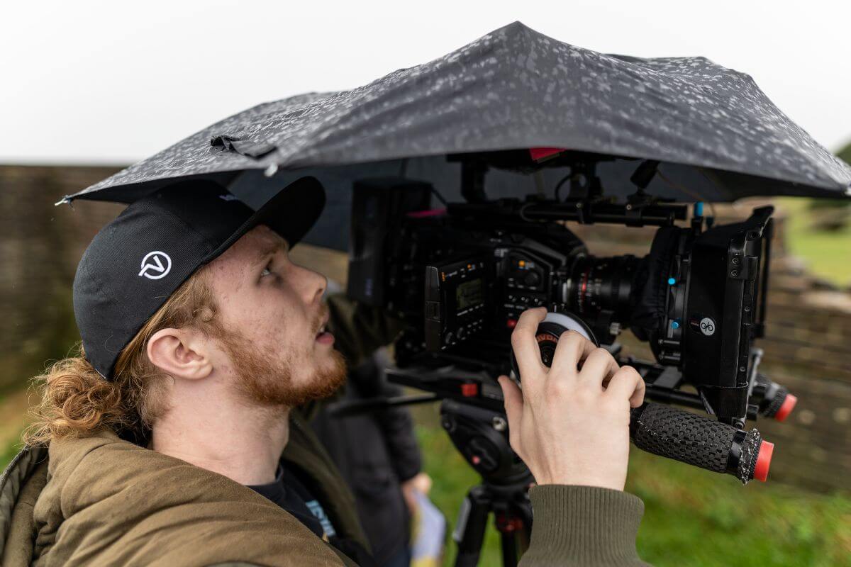 A cameraman capturing moments under an umbrella