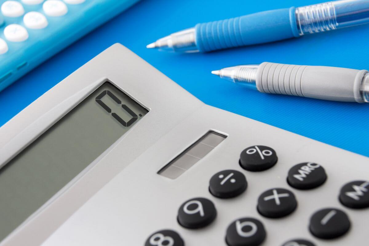 A calculator and pens on a blue background