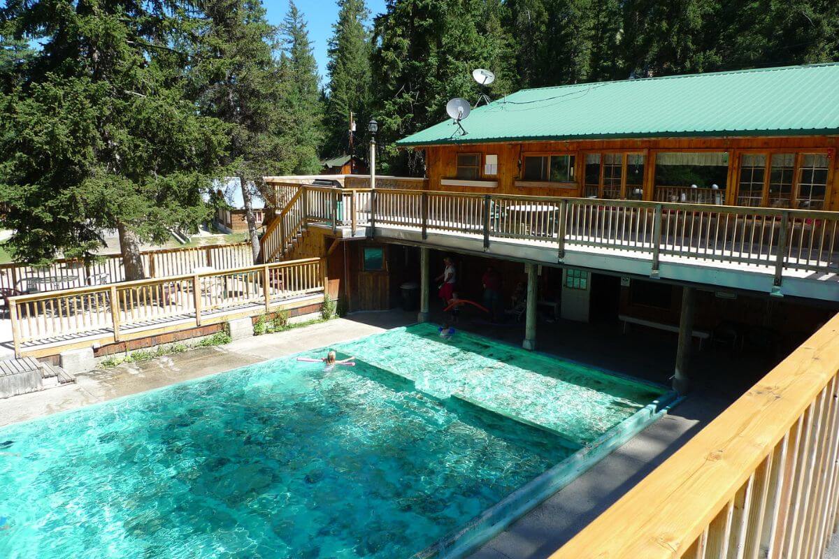 A popular hot spring in Montana features a wooden balcony with a view overlooking the pool.