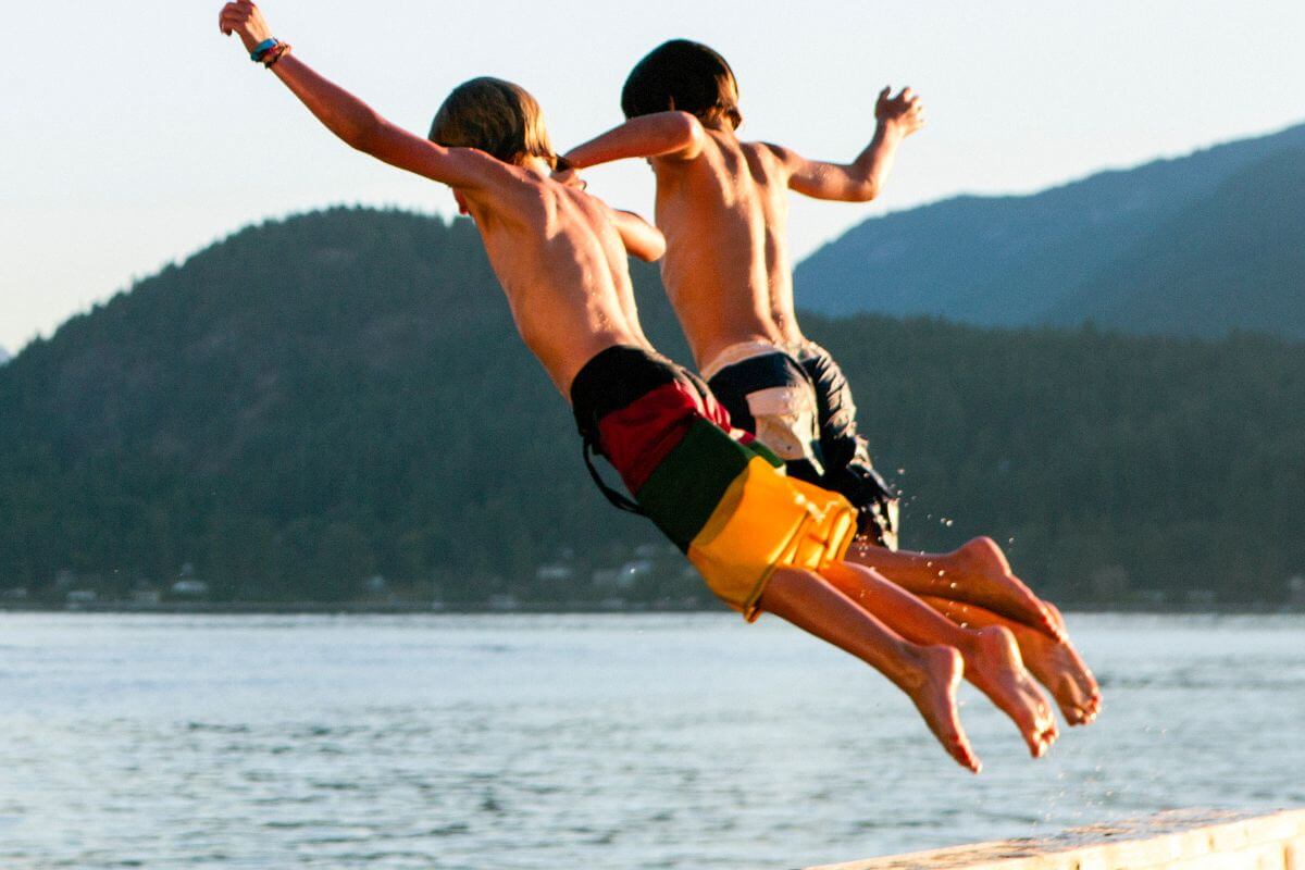 Two children jump excitedly into Lake McDonald during a Montana summer






