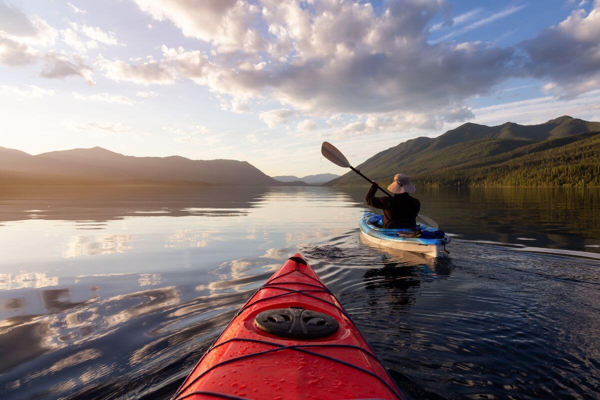 A person kayaks on Josephine Lake with a view of distant mountains under a clear sunset sky.





